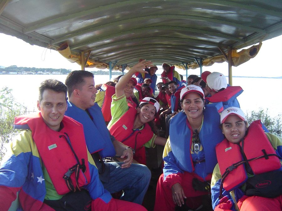 Grupo de participantes y facilitadores con chalecos salvavidas, sonriendo dentro de una lancha durante el traslado de un programa recreativo corporativo